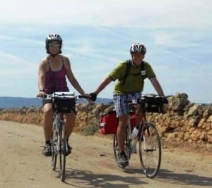 Two cyclists join hands on a Tuscan bike path