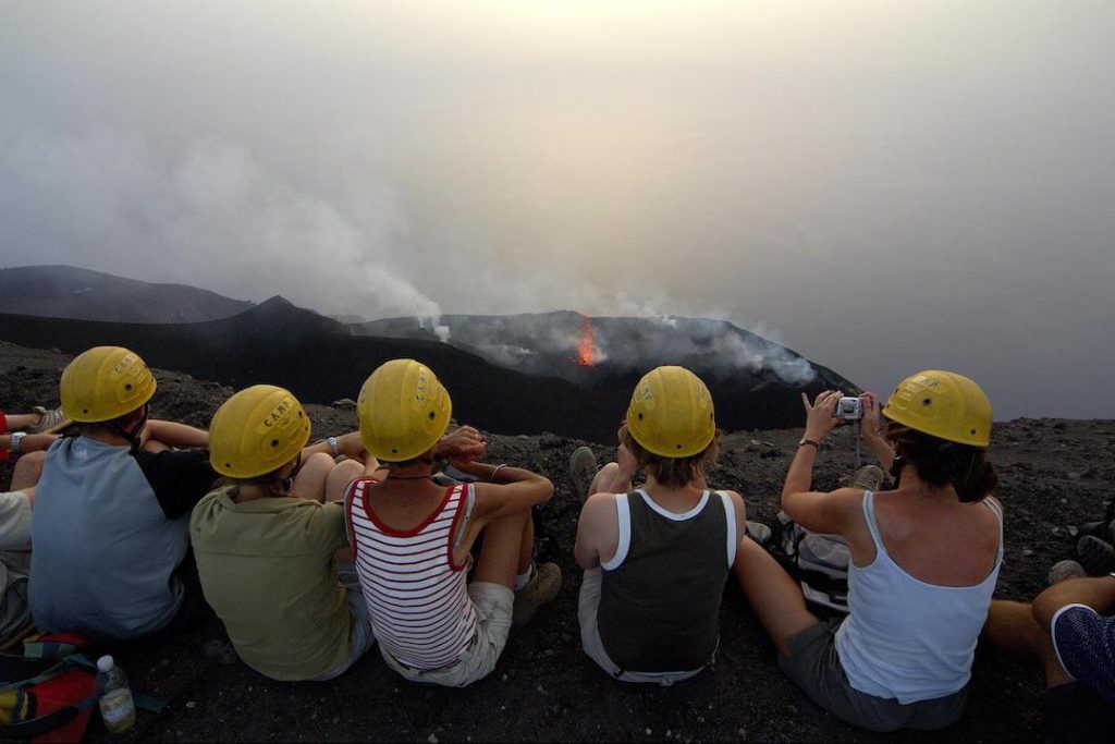A group of teenagers sits along a ridge of Mount Etna