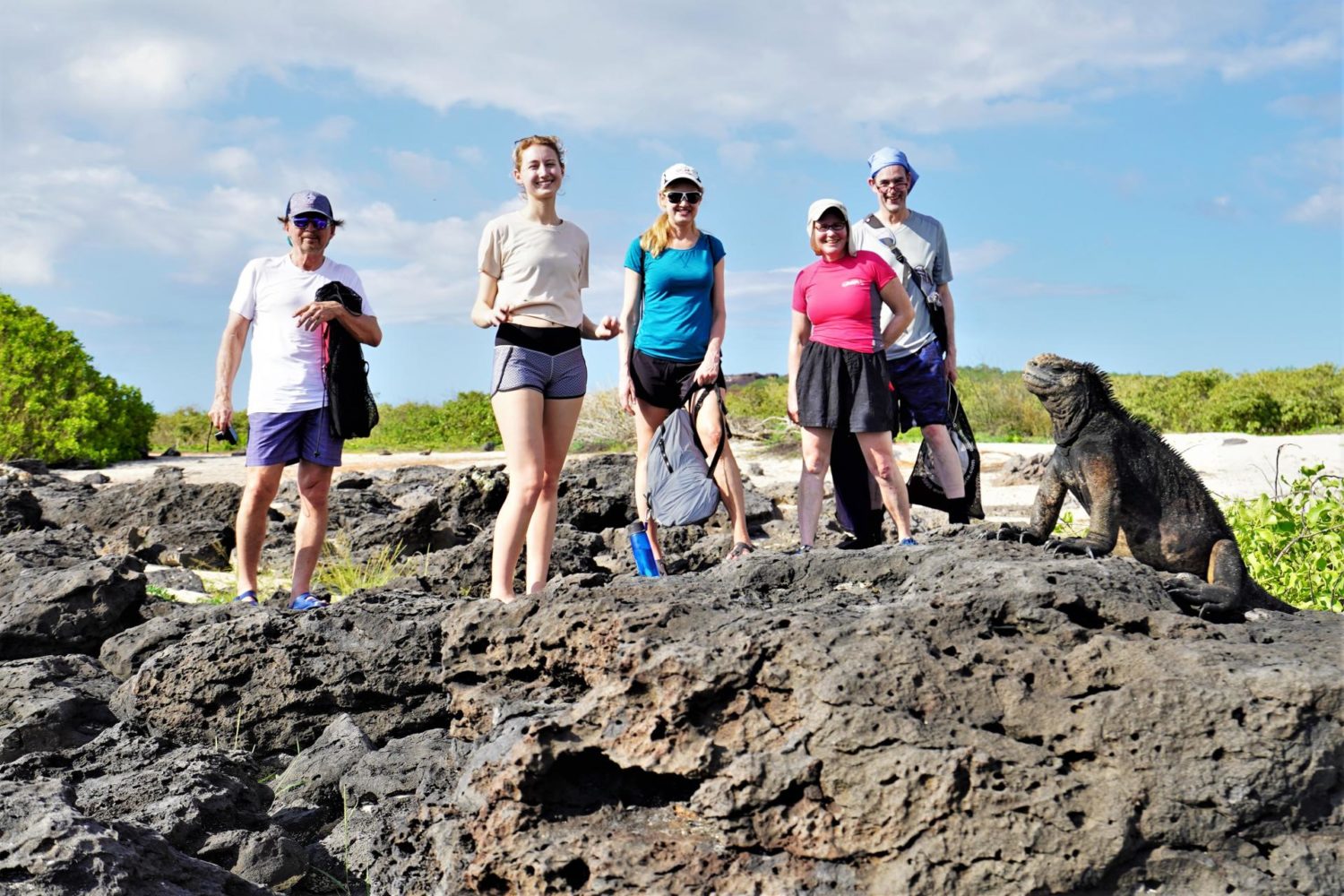 A family posing near a Galapagos iguana
